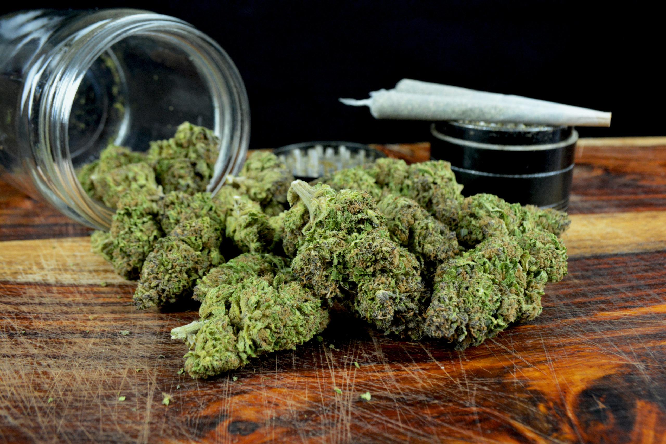 One ounce marijuana with jar, joints and grinder against black background